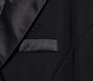 Dettaglio di un abito blazer nero con risvolto in raso e strass decorativi sulla tasca