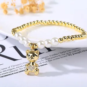 Macro shot of gold-plated beaded pearl bracelet with a micro-pave teddy bear charm