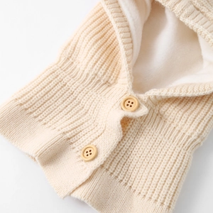 Close-up of winter baby knit hat showing thick white fleece lining and wooden buttons