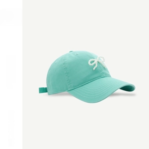 Detail shot of a mint green cotton baseball cap featuring a white pearl bow decoration