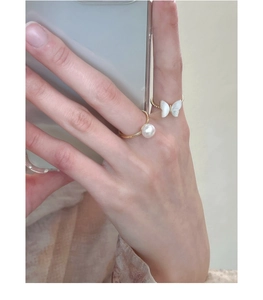 Close-up of elegant gold pearl ring and white butterfly ring worn by a model
