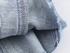 Vue macro détaillée du tissu denim bleu clair avec coutures précises et bords effilochés