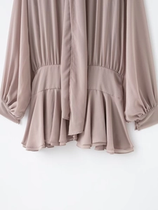 Detail of elegant lotus pink chiffon blouse with waist pleats and ruffled hem accents