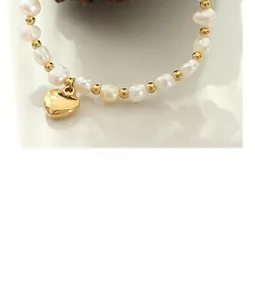 Macro detail of natural irregular pearls and gold beads with a heart pendant