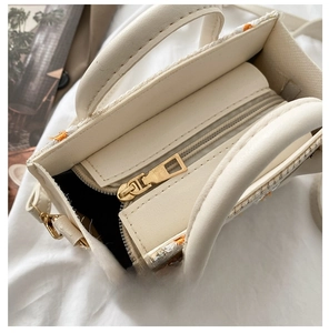 Detail view of the gold metal zipper pull and textured straw woven trim of the handbag