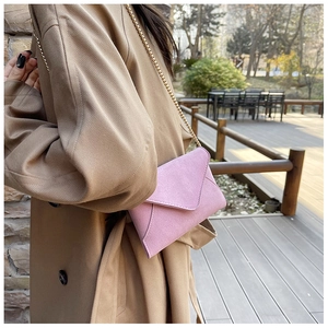 Pink frosted texture envelope bag with gold chain strap worn with a khaki trench coat