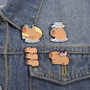 Detail of four cute cartoon capybara enamel pins on blue denim fabric background