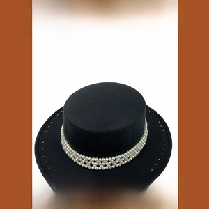 Detalle de sombrero boater de lana negra con elegantes adornos de perlas multicapa