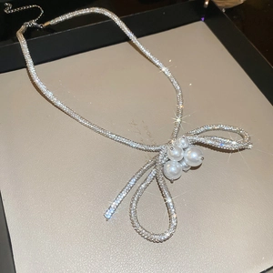 Detailed macro view of silver bow pendant with sparkling rhinestones and pearls