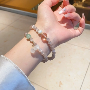 Detailed close-up of grey cat-eye stone bead bracelets with pearls on a female wrist