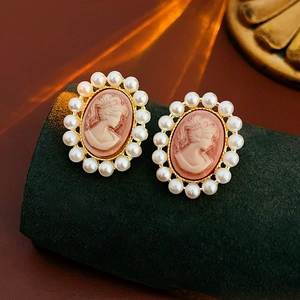 Détail de boucles d'oreilles camée vintage avec perles sur support en velours