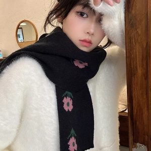 Elegant knit scarf with pink floral patterns on black background worn by a model