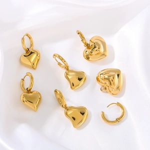 Polished gold hollow heart-shaped earrings and pendants on white silk background