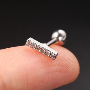 Macro shot of silver zircon bar earring with secure screw ball backing on fingertip