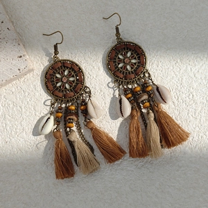 Macro detail of bohemian fringe earrings with vintage metal discs and natural shells