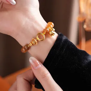 Bracciale in citrino con ciondoli di loto dorati sul polso di una donna in stile rétro