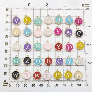 Detailed view of colorful enamel letter charms with mm scale for size reference