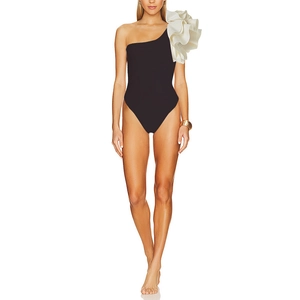 Detail of elegant one-shoulder swimsuit with tiered white ruffle trim and black high-cut design