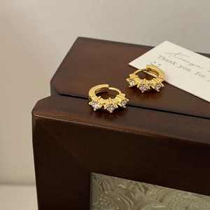 Macro view of gold hoop earrings with zircon stones on a vintage wooden background