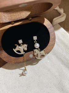 Detailed close-up of gold-plated rocking horse earrings with pearls and crystals