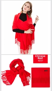 Detail of red cashmere scarf with fringe and classic brand label on white background