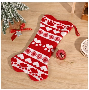 Close-up of red and white bone-shaped knitted Christmas stocking with paw and heart patterns