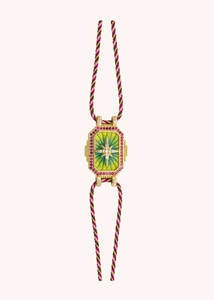 Macro shot of a magenta and gold braided bracelet with a green hexagonal charm and star