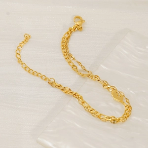 Double-layered golden Figaro chain anklet with geometric G-pendant on marble stand