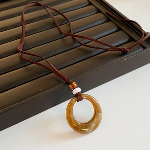 Close-up of vintage resin round amber pendant necklace with decorative beads and cord