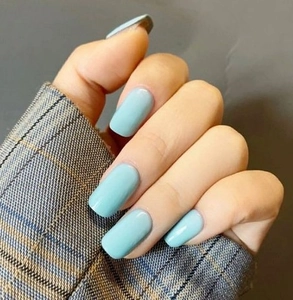 Close-up of mint blue glossy press-on nails on hands with gray checkered sleeve