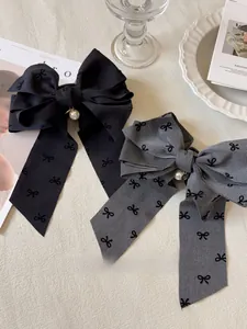 Dettaglio di fermagli per capelli in tessuto grigio e nero con eleganti perle