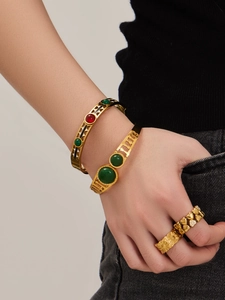 Macro shot of gold plated cuffs and rings with inlaid natural stones and floral motifs
