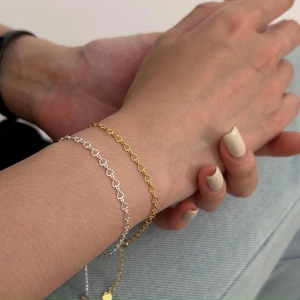 Detailed shot of gold and silver heart chain bracelets on wrist with denim background