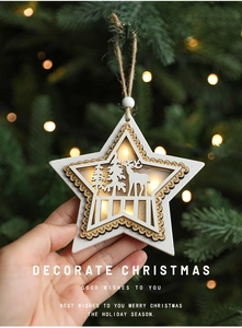 Glow-in-the-dark wooden Christmas star pendant with elk engraving held by hand