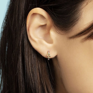 Close-up of gold pig nose hoop earring with colorful zircon stones on ear