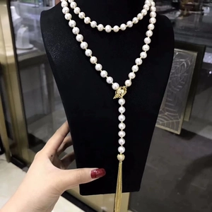 Elegant white pearl necklace with golden tassel pendant displayed on a black bust stand