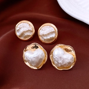 Détail de boucles d'oreilles perles plaquées or 16K et cœurs sur velours rouge