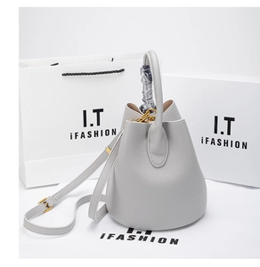 Close-up of light gray pebbled leather bucket bag with silk scarf handle detail