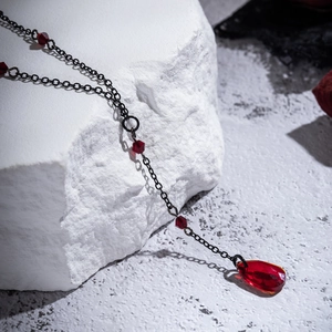Detailed macro view of Gothic blood-red teardrop crystal pendant on black metal chain