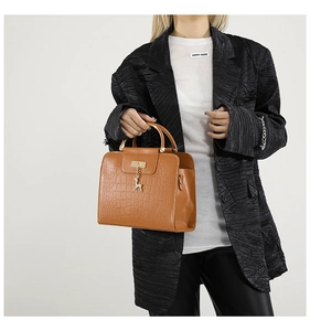 Détail d'un sac à main marron à motif crocodile avec breloque cerf doré et poignée