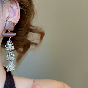 Détails de boucles d'oreilles carrées en bois avec cloches argentées sur l'oreille