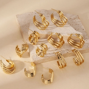 Collection of golden triple-layered stainless steel hoop earrings on stone pedestals