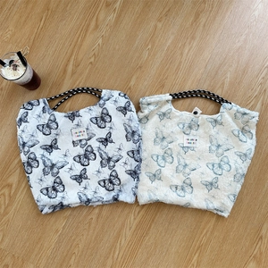 Macro detail of plush butterfly print tote bags with textured fabric and woven handles