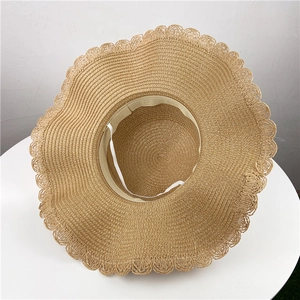 Detail view of straw sun hat featuring wavy scalloped edges and adjustable wind rope