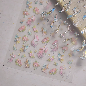 Detailed relief nail sticker with golden phoenix and floral patterns on white background