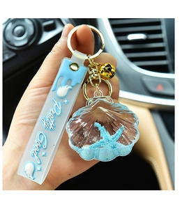 Detail of blue acrylic seashell keychain with floating starfish and Pretty Good strap