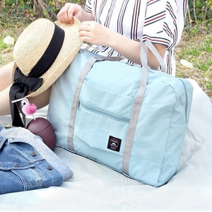 Sky blue foldable travel duffel bag for luggage handles shown in an outdoor picnic setting