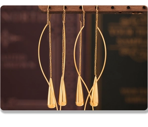 Macro detail of gold-plated waterdrop tassel earrings featuring polished metal finish