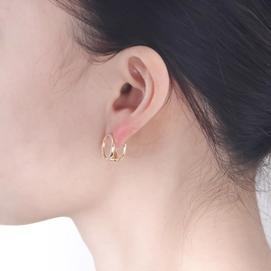 Minimalist double hoop titanium earrings in gold with pavé cubic zirconia worn by a model