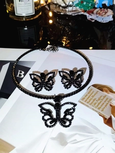 Detailed view of gothic black butterfly necklace and stud earrings set on magazine